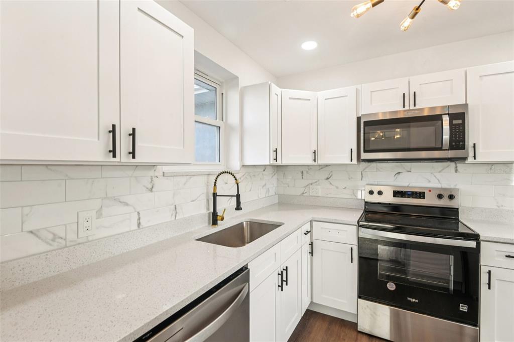 410 Virginia Avenue Madeira Beach, FL 33708 - Photo 10 of 25 a kitchen with stainless steel appliances a stove a sink a microwave and cabinets