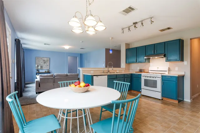 a view of a dining room with furniture a kitchen and chandelier