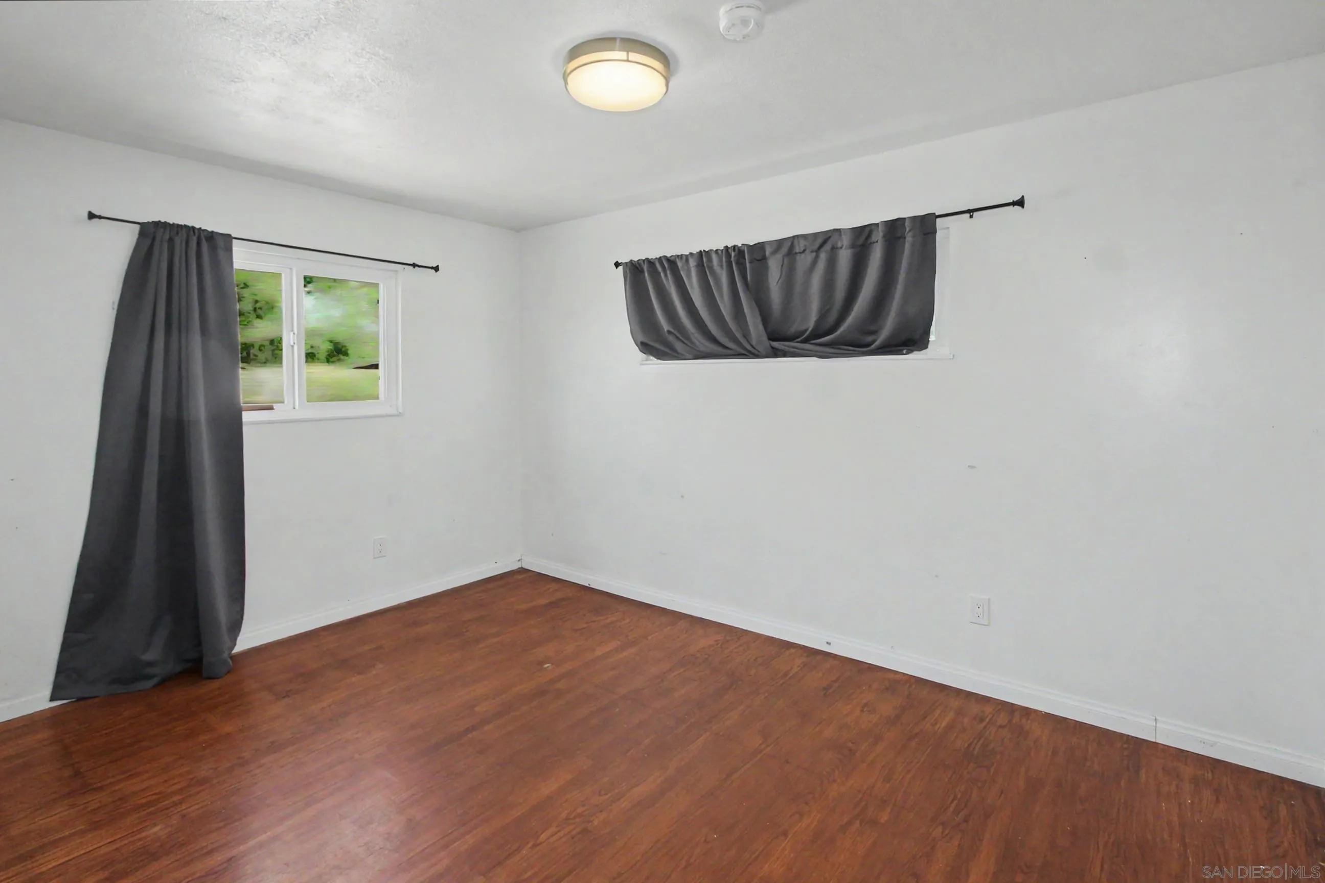 8766 Kelso Street Spring Valley, CA 91977 - Photo 25 of 44 an empty room with wooden floor and windows