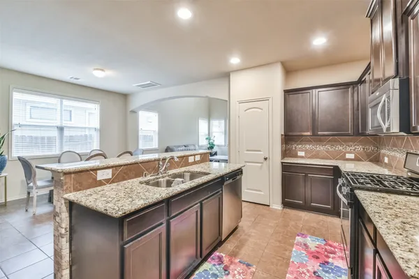 a kitchen with granite countertop kitchen island stainless steel appliances a sink stove and cabinets