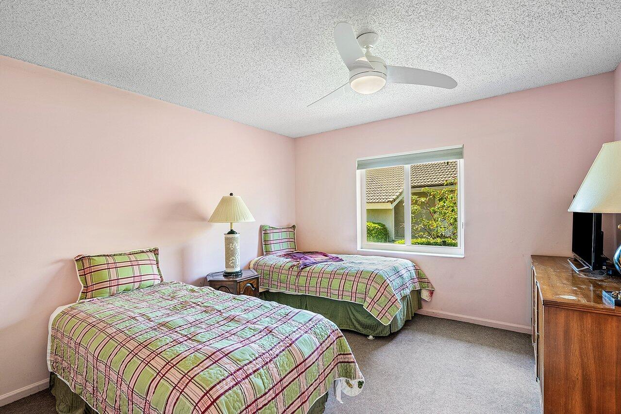 10215 Boca Woods Lane Boca Raton, FL 33428 - Photo 14 of 22 a bedroom with two beds and a chandelier