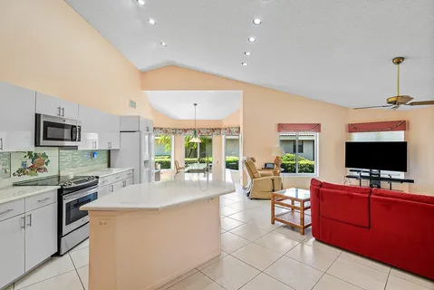 a living room with stainless steel appliances kitchen island granite countertop a sink and cabinets