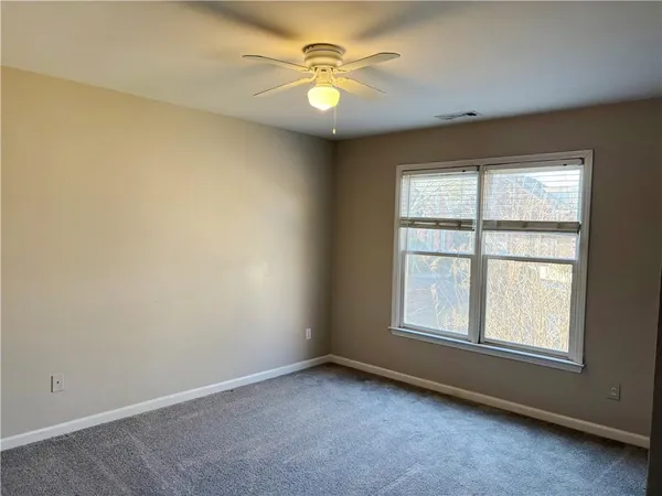 an empty room with windows and fan
