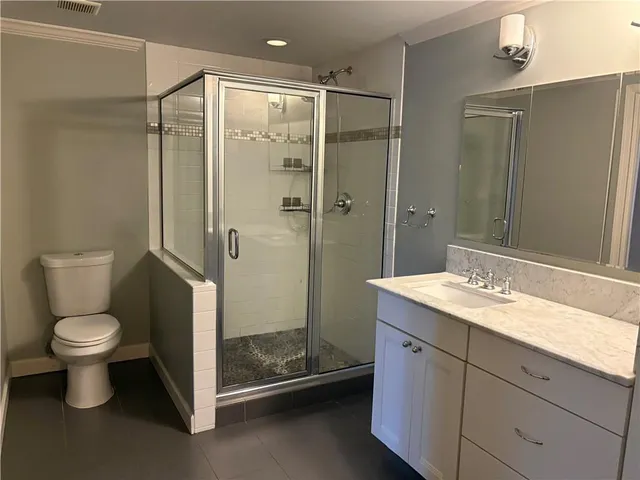 a bathroom with a granite countertop sink toilet and shower