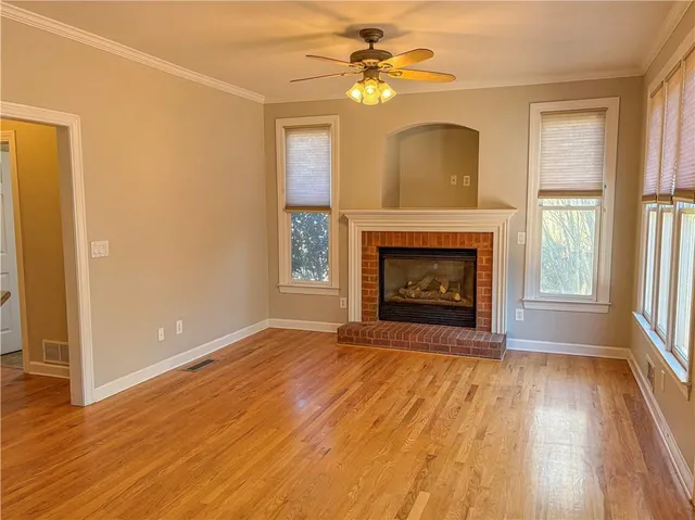 an empty room with windows a fireplace and wooden floor