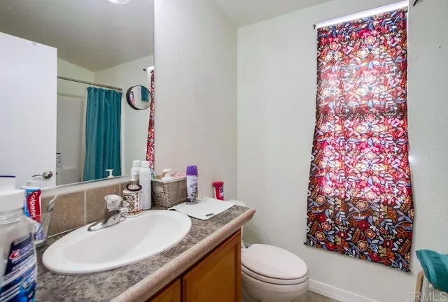 a bathroom with a granite countertop toilet a sink and a mirror