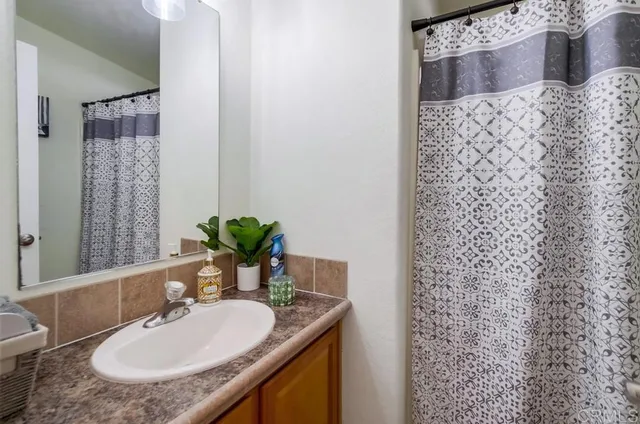 a bathroom with a granite countertop sink a mirror and a shower