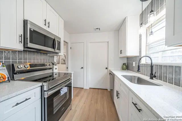 a kitchen with stainless steel appliances a stove microwave and sink