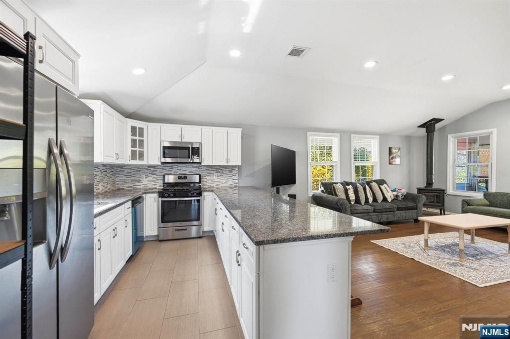6 Timberwood Lane Oak Ridge, NJ 07438 - Photo 10 of 44 a kitchen with stainless steel appliances granite countertop a refrigerator a stove a sink a dining table and chairs