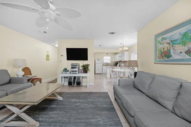 a living room with furniture and a flat screen tv with kitchen view