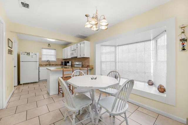 a kitchen with a dining table chairs and refrigerator