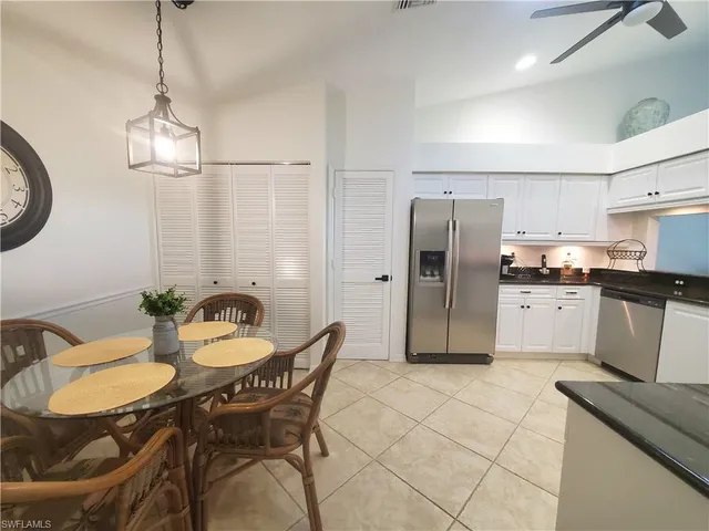 a kitchen with stainless steel appliances a dining table chairs refrigerator and sink