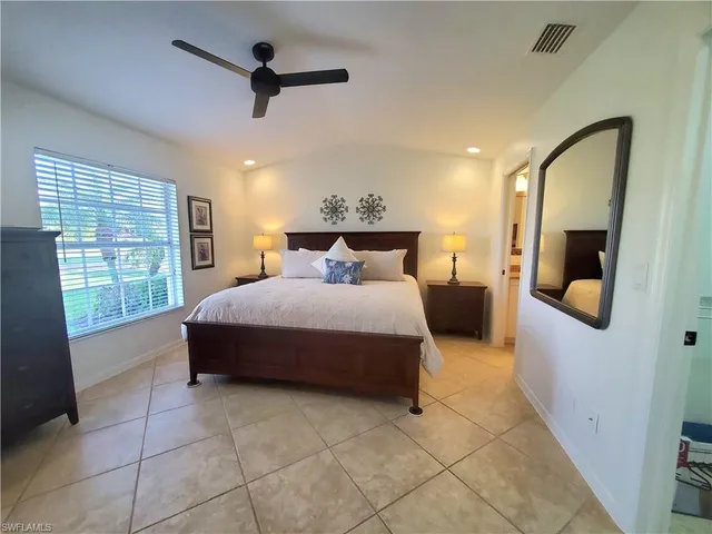 a spacious bedroom with a bed a chandelier and large window