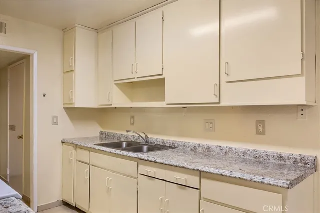 a kitchen with granite countertop white cabinets and a sink