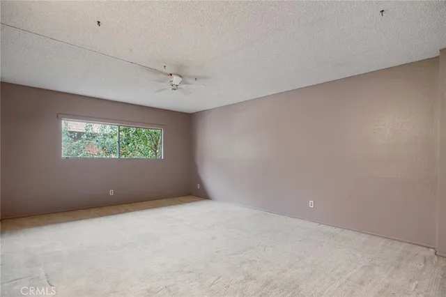 an empty room with windows and a ceiling fan