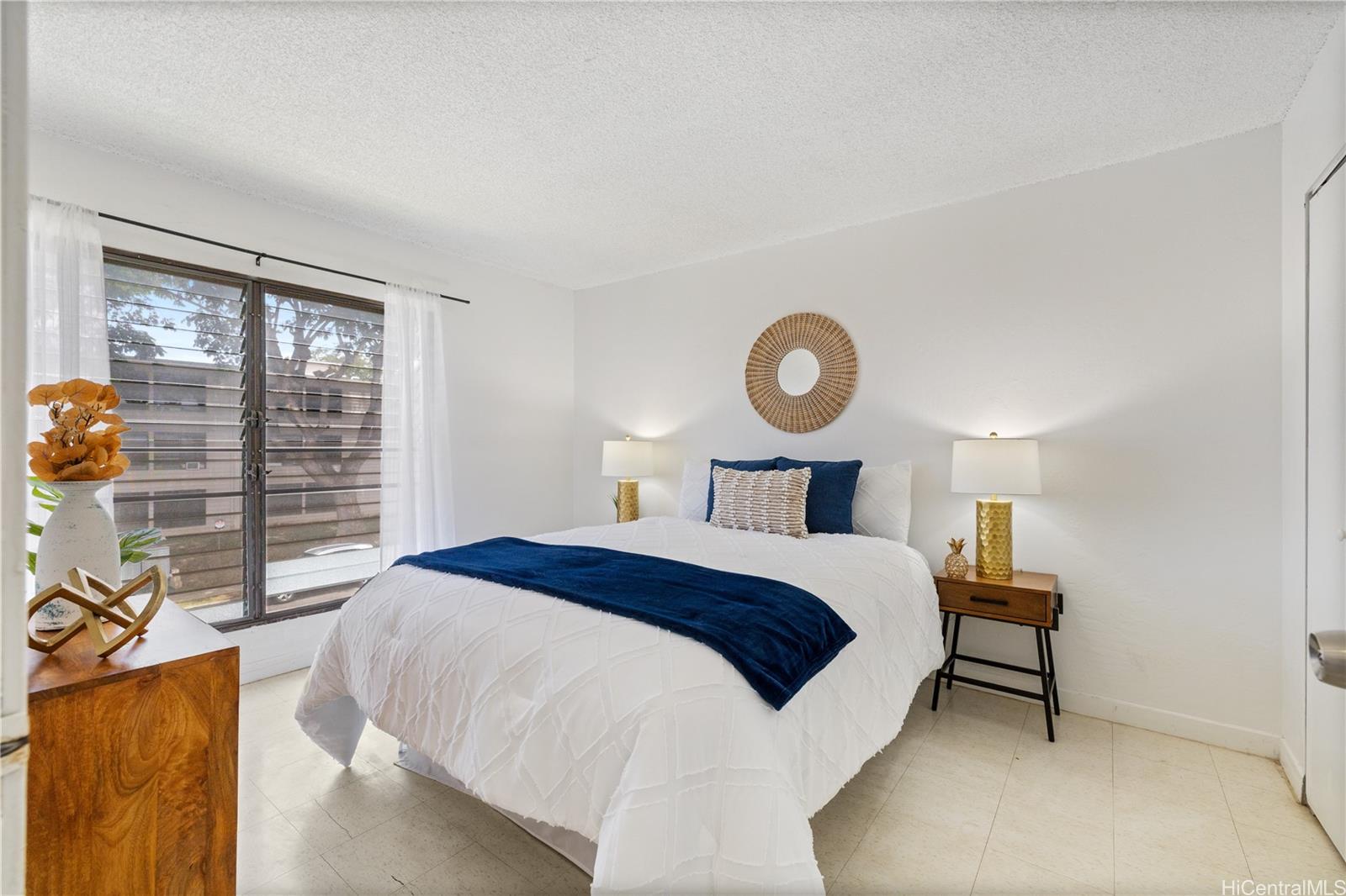 87-119 Helelua Street, Unit F204 Waianae, HI 96792 - Photo 11 of 24 a bedroom with a bed a mirror and a window