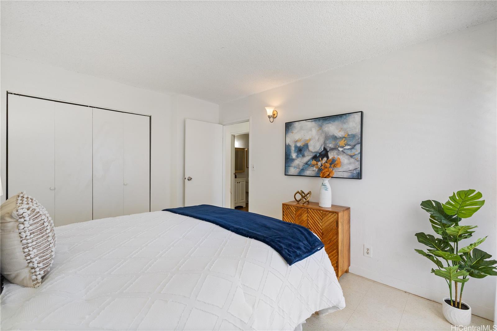 87-119 Helelua Street, Unit F204 Waianae, HI 96792 - Photo 12 of 24 a bedroom with a bed and a potted plant