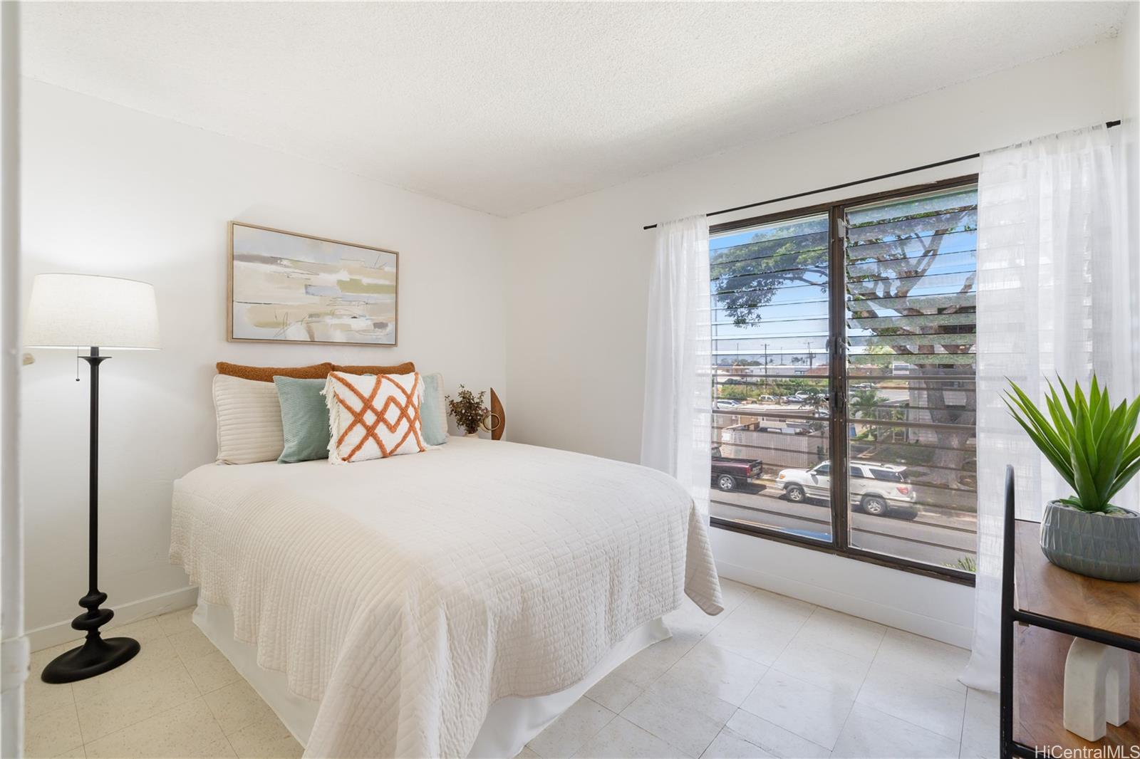 87-119 Helelua Street, Unit F204 Waianae, HI 96792 - Photo 15 of 24 a bedroom with a large bed and a potted plant