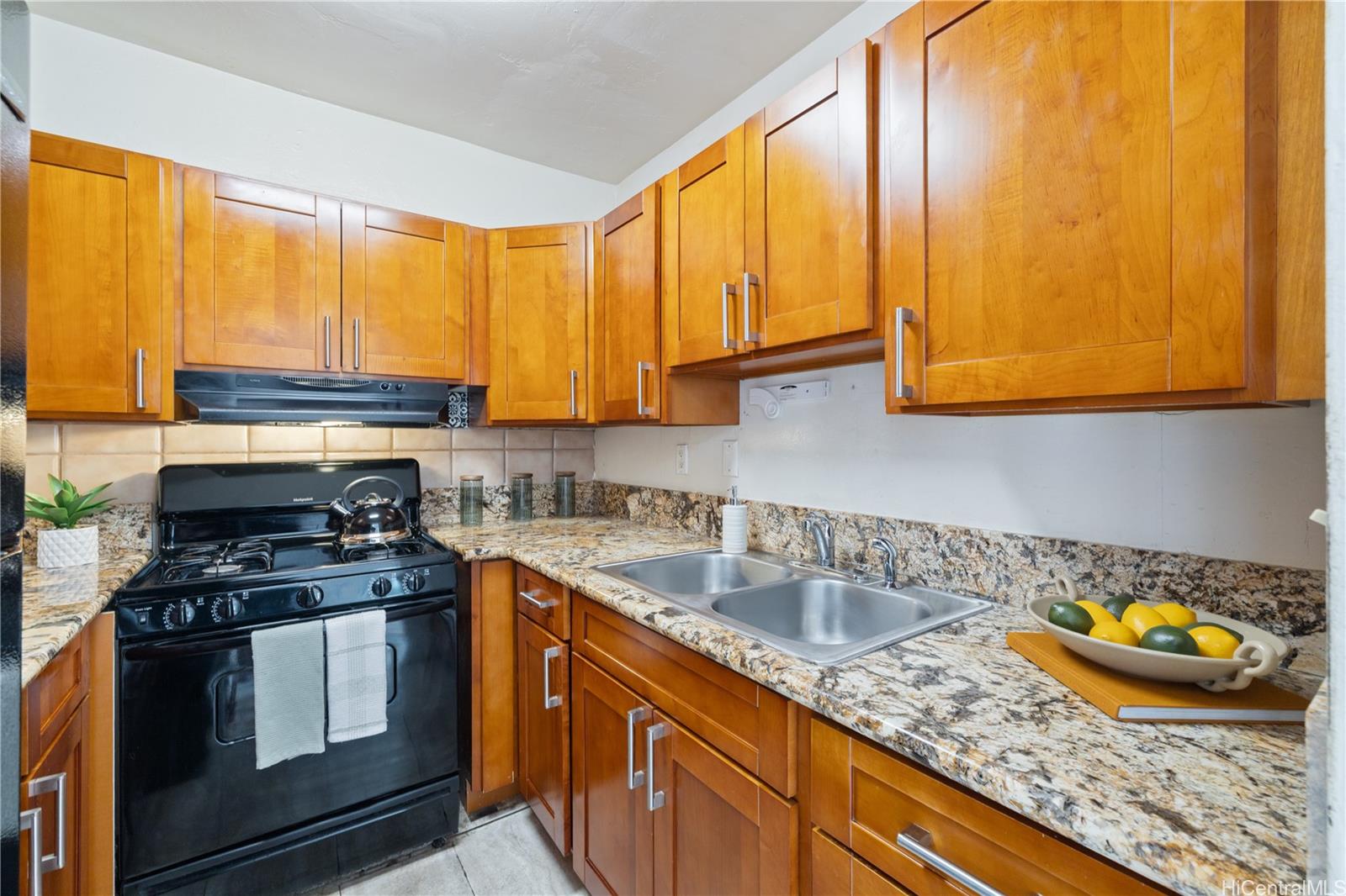 87-119 Helelua Street, Unit F204 Waianae, HI 96792 - Photo 6 of 24 a kitchen with stainless steel appliances granite countertop a stove a sink and a microwave