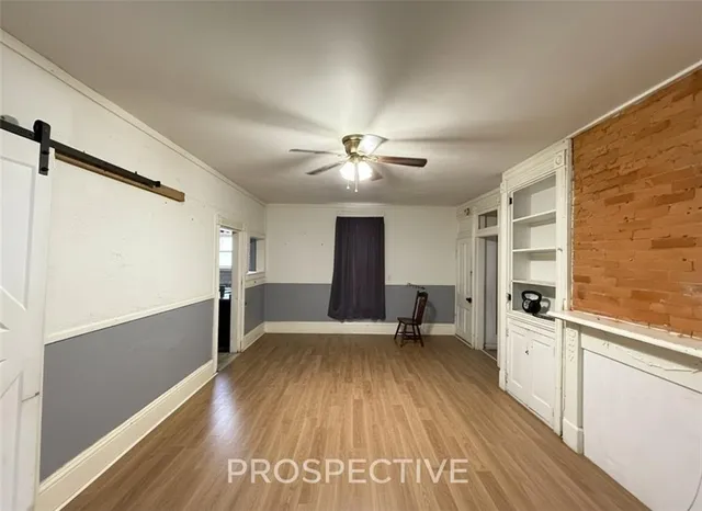 a view of a room with wooden floor a ceiling fan and windows