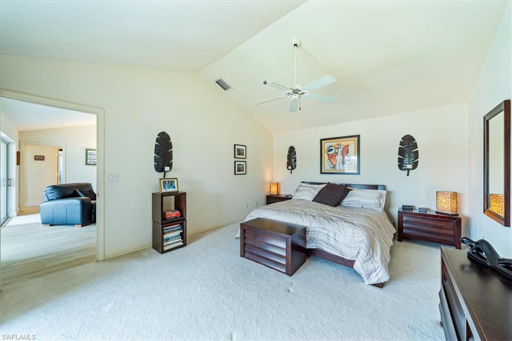 231 Via Perignon, Unit 204 Naples, FL 34119 - Photo 19 of 26 a spacious bedroom with a bed and a chandelier
