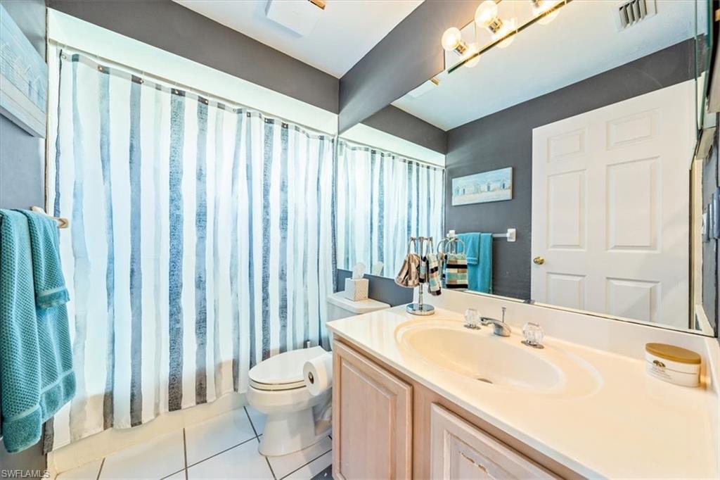 231 Via Perignon, Unit 204 Naples, FL 34119 - Photo 24 of 26 a bathroom with a sink a toilet and shower curtain