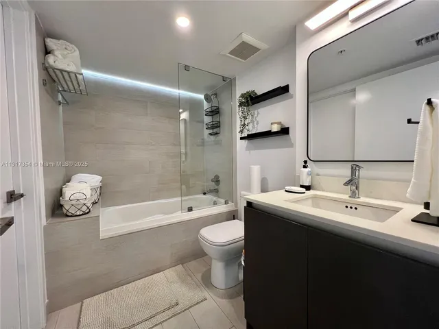 a bathroom with a double vanity sink toilet mirror and shower