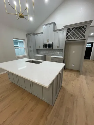 a kitchen with stainless steel appliances kitchen island a wooden floor and white cabinets