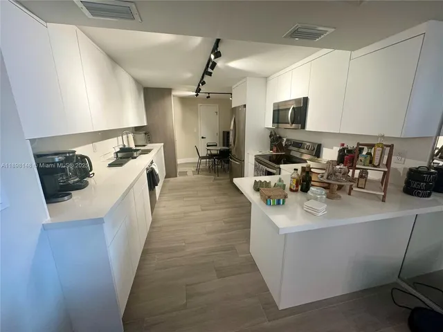 a kitchen with stainless steel appliances granite countertop a sink a stove top oven a chimney wooden floor and cabinets