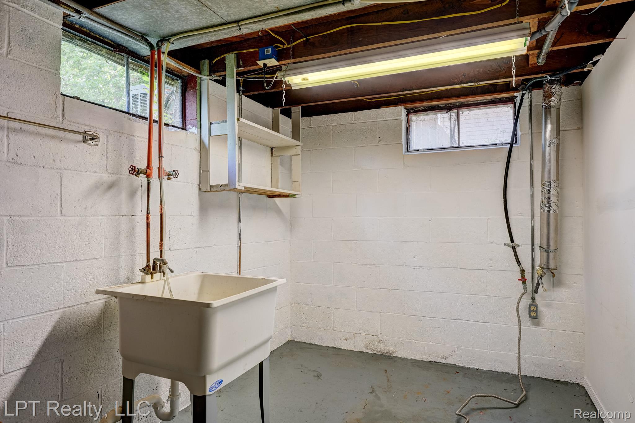 23038 Violet Street Farmington, MI 48336 - Photo 25 of 29 Utility sink with exposed copper plumbing, set against white painted concrete block walls