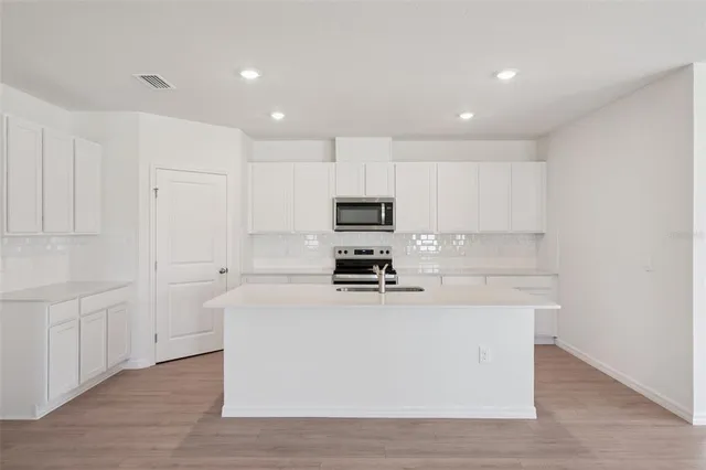 a white kitchen with wooden floor and cabinets