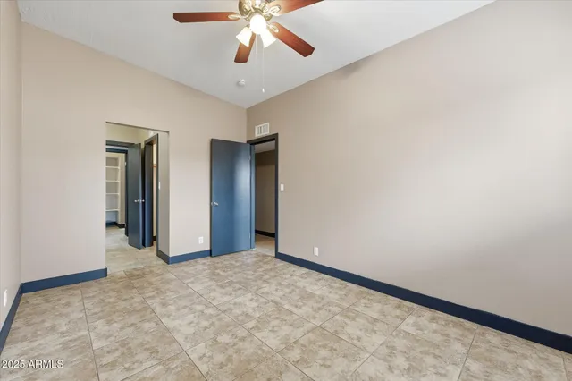 an empty room with a chandelier fan and windows