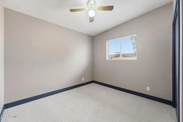 an empty room with windows and ceiling fan