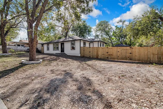 a view of a backyard with large trees and a barn