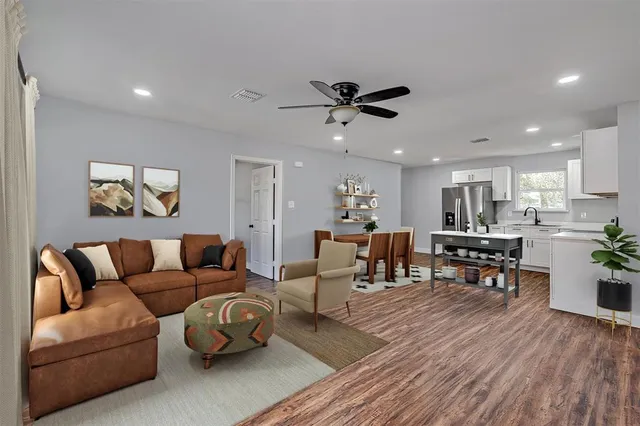 a living room with furniture kitchen view and a wooden floor