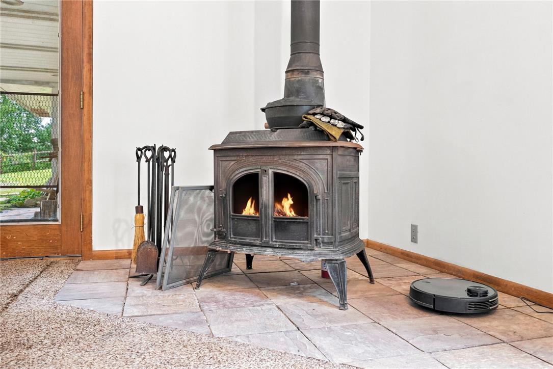 3408 Oak Hill Road Emmaus, PA 18049 - Photo 16 of 93 A classic wood stove sits on a raised stone hearth beside glass-paneled doors.