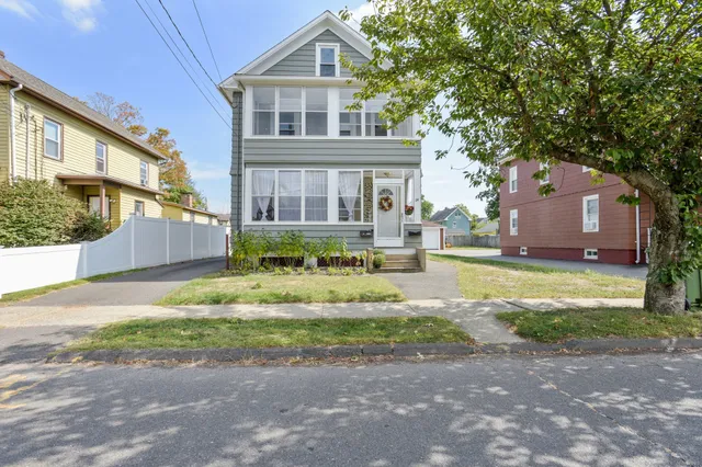 a front view of a house with a yard and potted plants