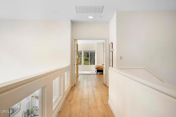 a view of a hallway with wooden floor and a bathroom