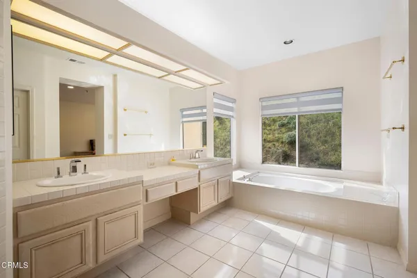 a spacious bathroom with a double vanity sink a large mirror and a bathtub
