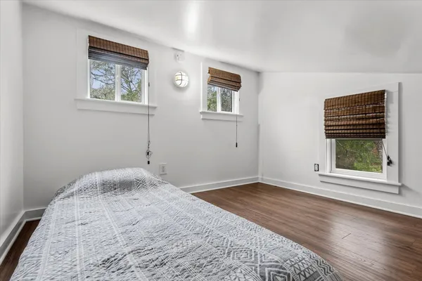 a view of a bedroom with wooden floor and windows