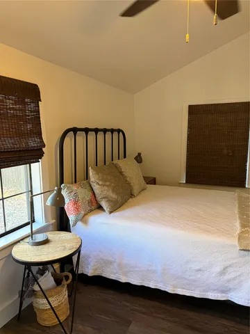 a bedroom with a bed a dresser and wooden floor