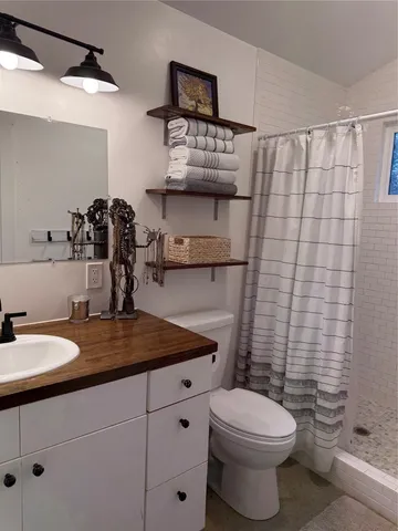 a bathroom with a granite countertop toilet sink and mirror