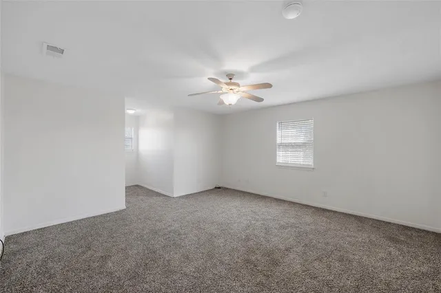 an empty room with windows and fan