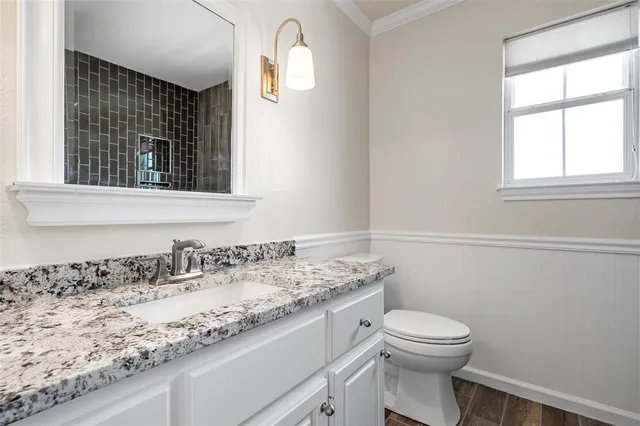 a bathroom with a granite countertop sink a toilet and a window