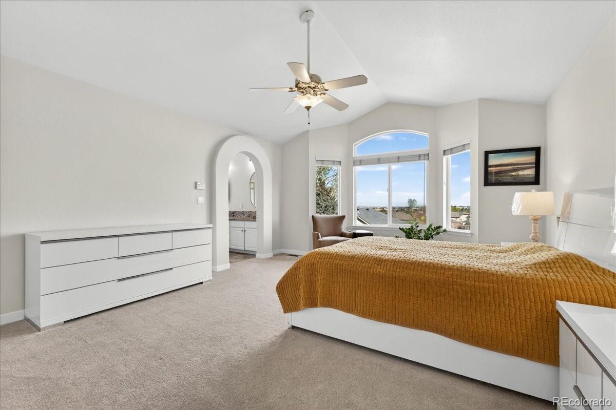 9477 Burgundy Circle Highlands Ranch, CO 80126 - Photo 23 of 50 a spacious bedroom with a bed and a chandelier