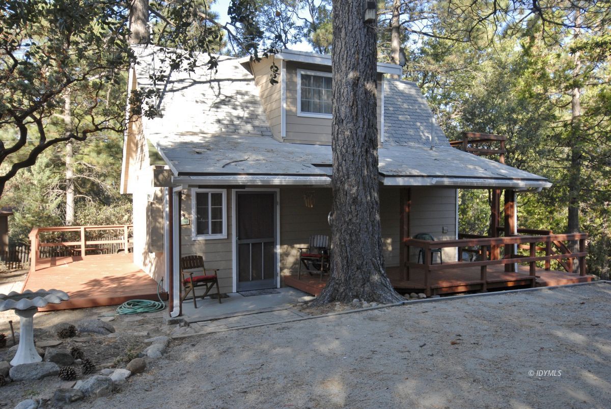 a view of a house with a barbeque and a large tree
