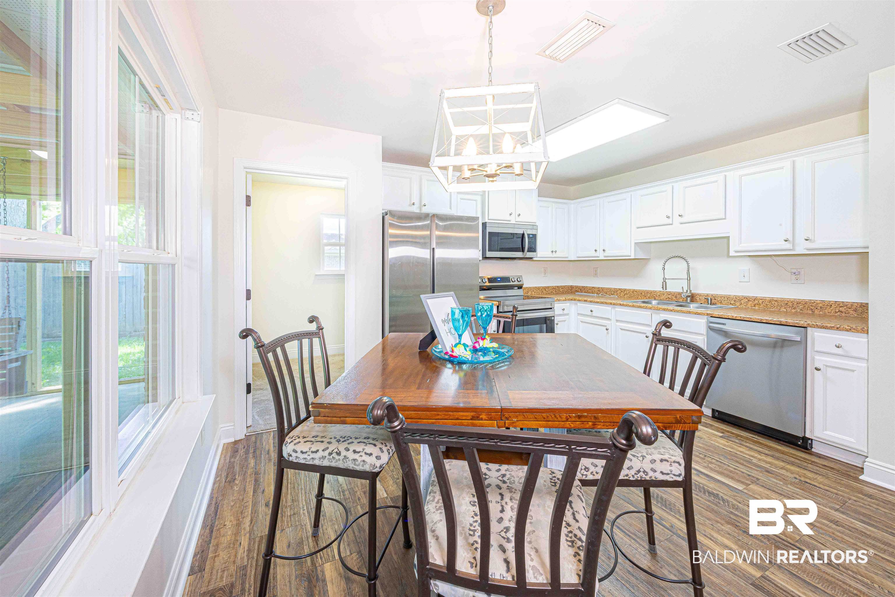 18675 Explorer Drive Loxley, AL 36551 - Photo 16 of 42 Dining space featuring dark wood-style floors, a chandelier, plenty of natural light, and baseboards