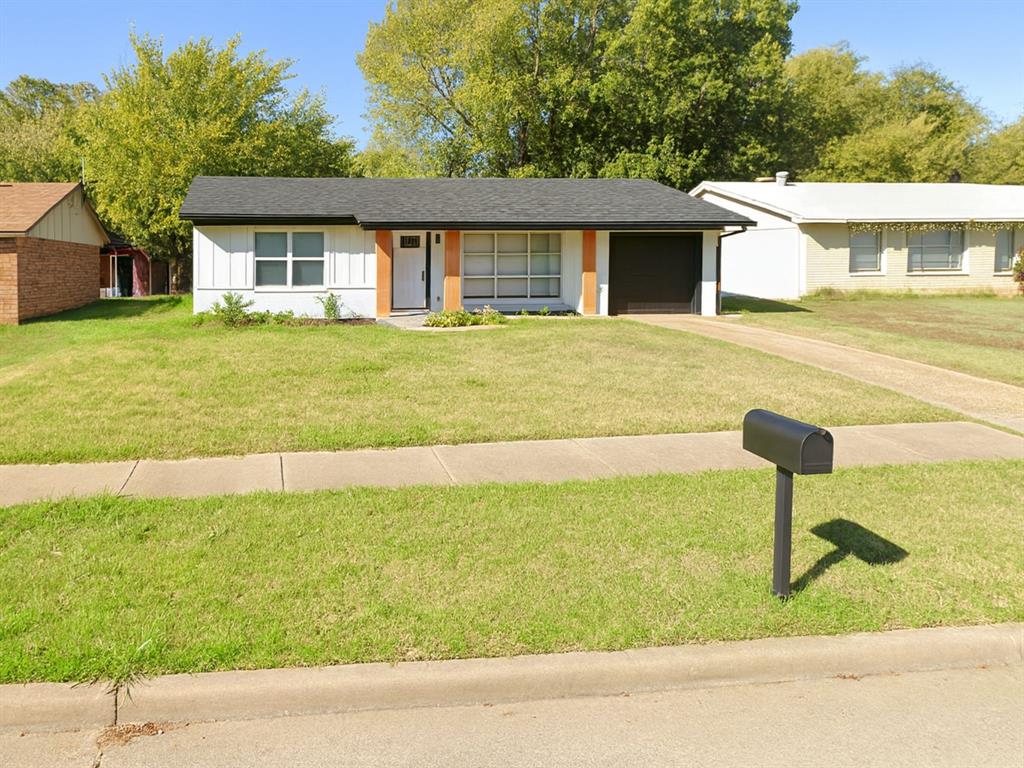 Ranch-style home with a front yard, concrete driveway, a shingled roof, and board and batten siding