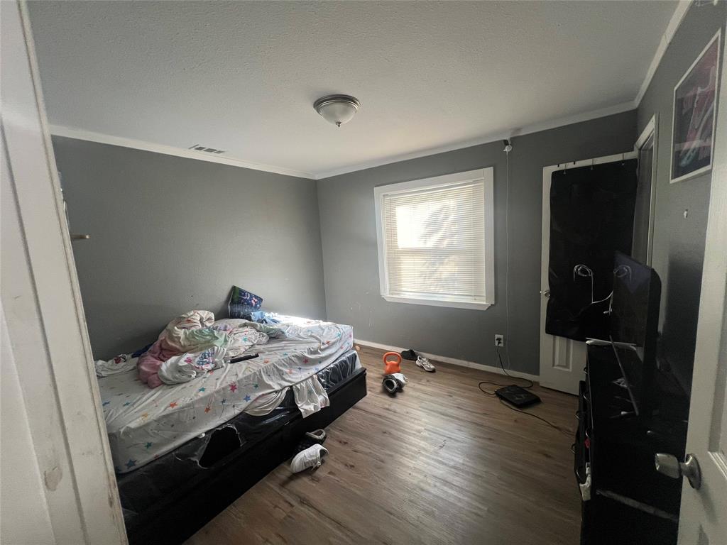 1722 Proctor Street Grand Prairie, TX 75051 - Photo 20 of 39 Bedroom featuring crown molding, wood finished floors, and a textured ceiling