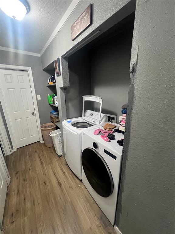 1722 Proctor Street Grand Prairie, TX 75051 - Photo 23 of 39 Washroom with a textured wall, wood finished floors, washing machine and dryer, and a textured ceiling